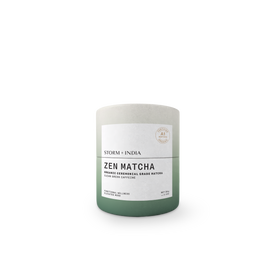 A cylindrical matcha tea tin with a matte finish, featuring a color gradient from light gray at the top to sage green at the bottom, with a white label reading 'ZEN MATCHA' and 'STORM + INDIA'.