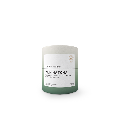 A cylindrical matcha tea tin with a matte finish, featuring a color gradient from light gray at the top to sage green at the bottom, with a white label reading 'ZEN MATCHA' and 'STORM + INDIA'.