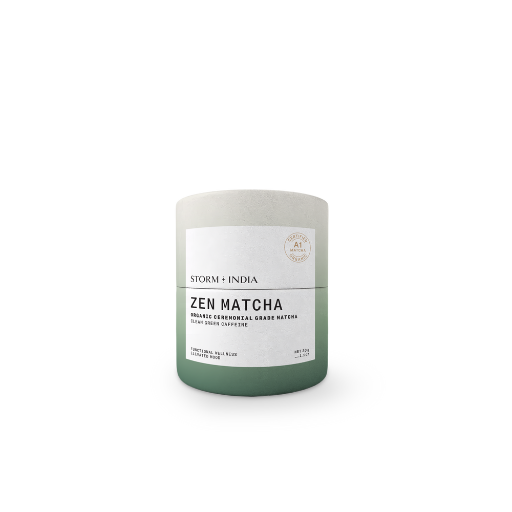 A cylindrical matcha tea tin with a matte finish, featuring a color gradient from light gray at the top to sage green at the bottom, with a white label reading 'ZEN MATCHA' and 'STORM + INDIA'.