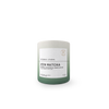 A cylindrical matcha tea tin with a matte finish, featuring a color gradient from light gray at the top to sage green at the bottom, with a white label reading 'ZEN MATCHA' and 'STORM + INDIA'.